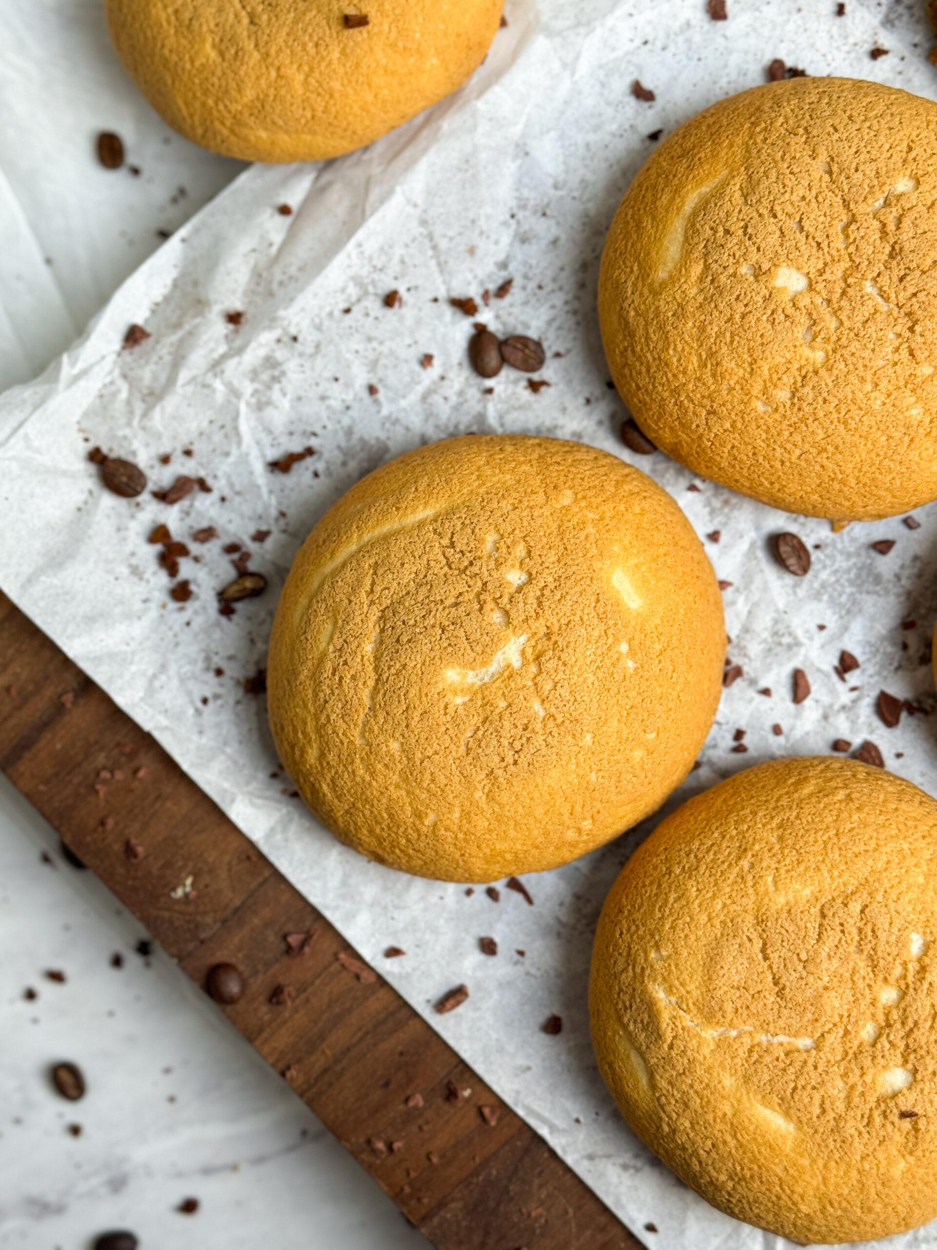 close up of papparoti coffee buns on a wooden serving board. they are big and fluffy with a crispy golden coffee crust on top